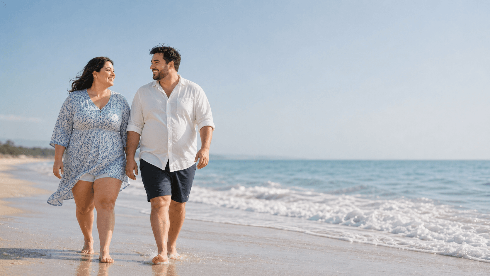 Couple walking on a beach, smiling at each other